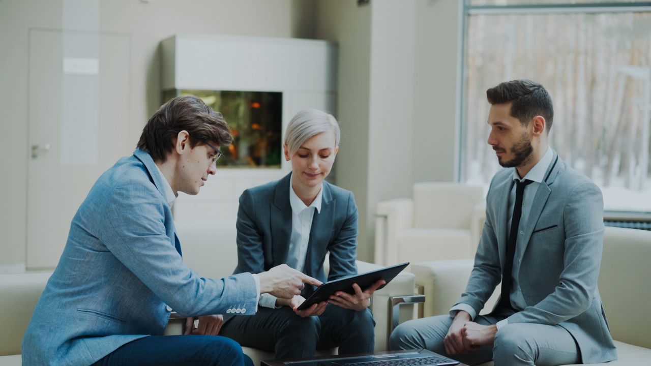 Mastering the First Impression: Your intriguing post title goes here Three professionals engaging in a business meeting in a modern office setting.