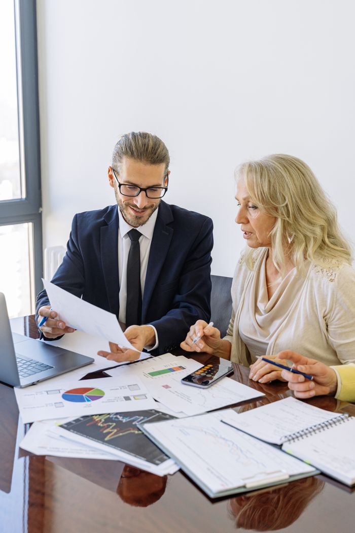 Home Two business professionals reviewing financial documents and graphs during a meeting.